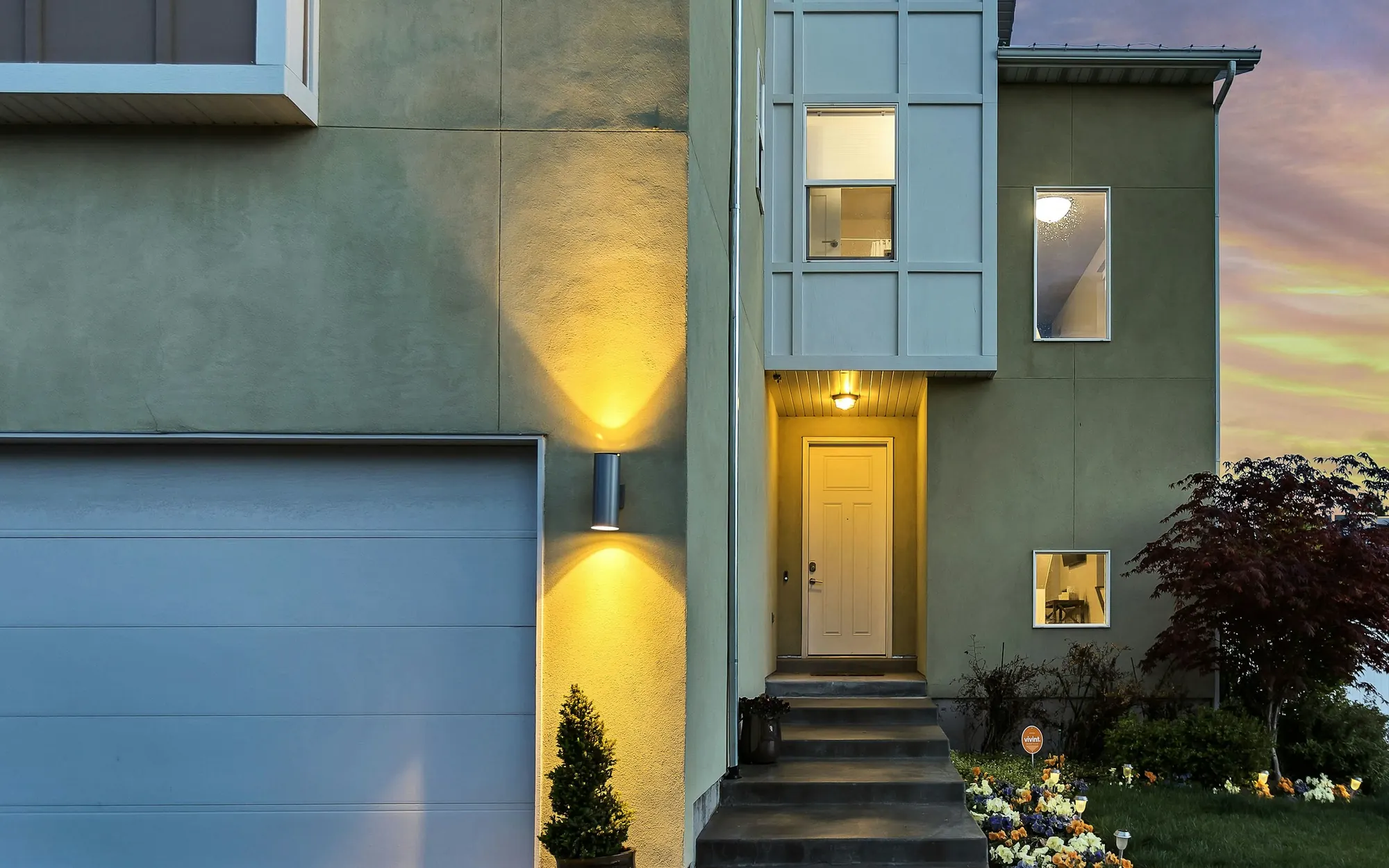 Home with its outdoor lights on at dusk